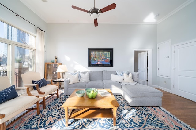 living room featuring wood finished floors, a ceiling fan, baseboards, and ornamental molding