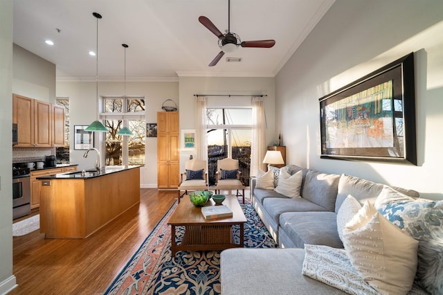 living room with a wealth of natural light, visible vents, dark wood-type flooring, and ornamental molding