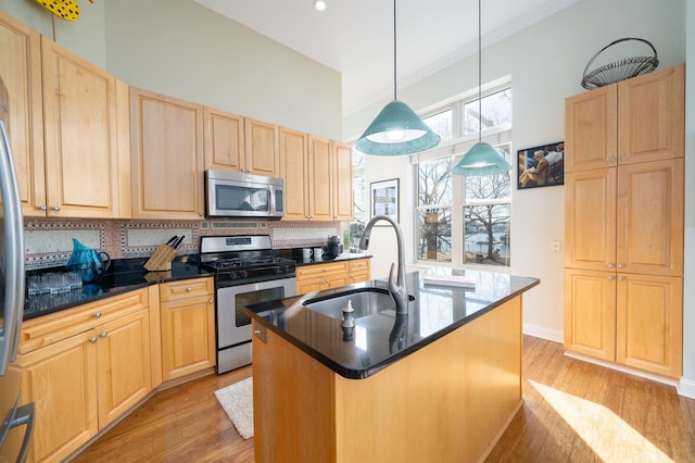 kitchen with backsplash, light brown cabinetry, light wood-style floors, stainless steel appliances, and a sink