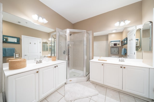 full bathroom featuring tile patterned floors, a stall shower, two vanities, and a sink