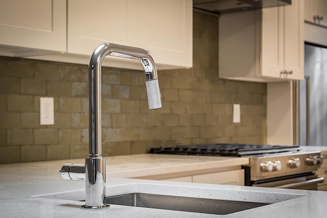 kitchen with backsplash, white cabinetry, extractor fan, and a sink