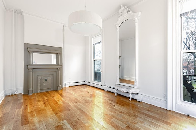 interior space with a wealth of natural light, light wood-style floors, and ornamental molding