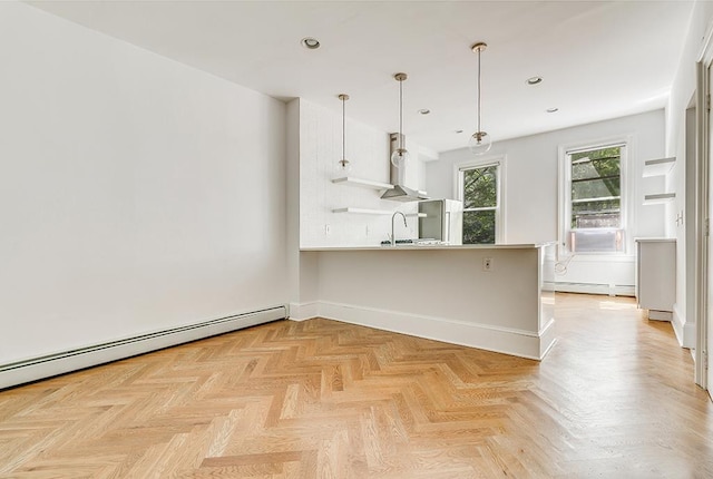 kitchen with a peninsula, decorative light fixtures, freestanding refrigerator, and a baseboard radiator