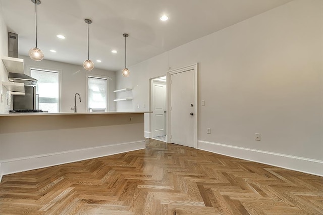 kitchen with pendant lighting, recessed lighting, a peninsula, wall chimney range hood, and baseboards