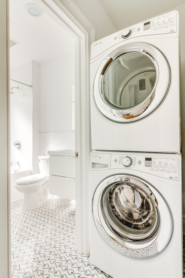 laundry area with tile patterned floors, laundry area, and stacked washer / drying machine