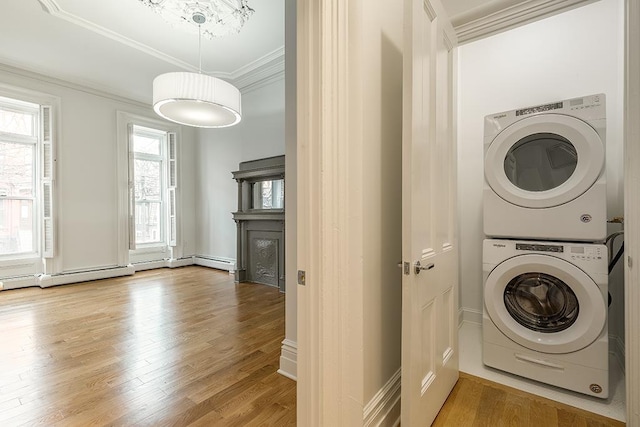 washroom featuring laundry area, a fireplace, ornamental molding, light wood-style floors, and stacked washer / drying machine