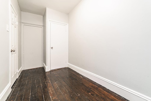 unfurnished bedroom with baseboards and dark wood-style floors