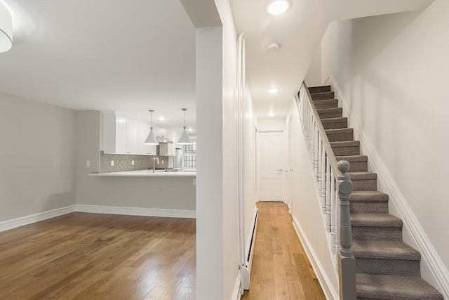 stairway featuring hardwood / wood-style flooring, recessed lighting, baseboards, and a baseboard radiator