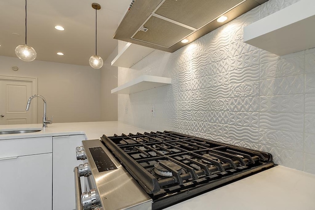 kitchen with a sink, open shelves, light countertops, decorative backsplash, and stainless steel range with gas stovetop