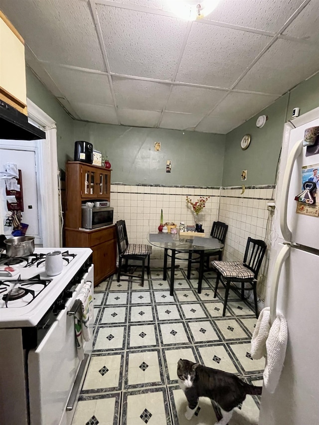 315 56th St Unit D4, West New York, NJ 07093 - kitchen featuring white appliances, a drop ceiling, tile walls, and wainscoting