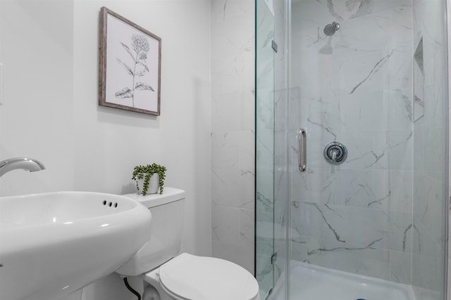 bathroom with toilet, a shower with door, and sink