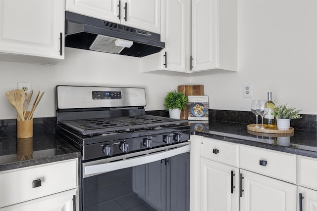 kitchen with dark stone counters, gas stove, and white cabinetry