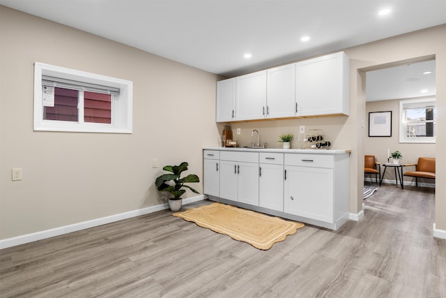 kitchen featuring sink, white cabinetry, and light hardwood / wood-style flooring