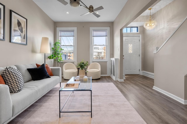 living room featuring ceiling fan with notable chandelier and hardwood / wood-style floors