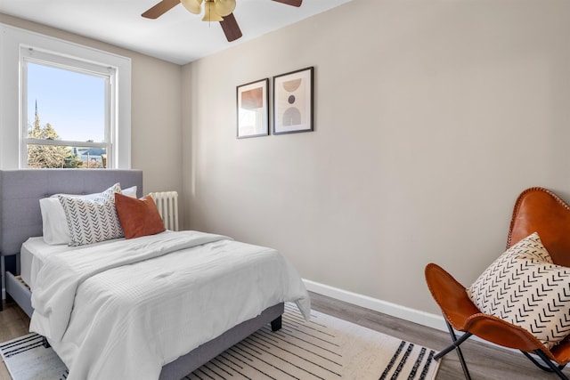 bedroom with radiator, wood-type flooring, and ceiling fan