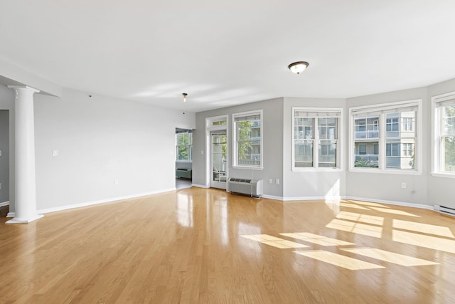 unfurnished living room with light hardwood / wood-style flooring and ornate columns