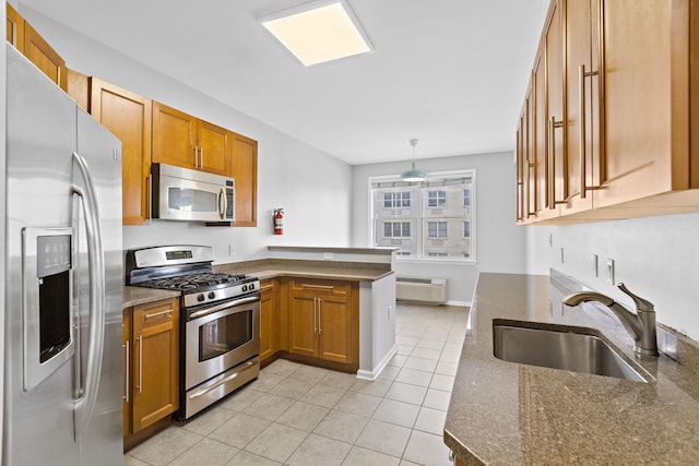 kitchen with appliances with stainless steel finishes, sink, hanging light fixtures, kitchen peninsula, and light tile patterned floors