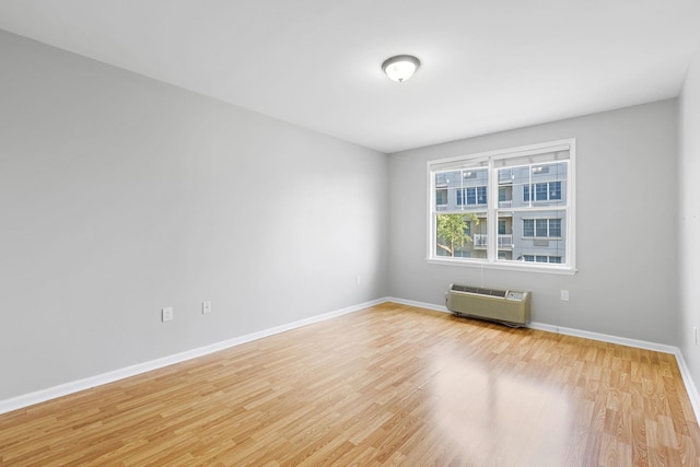 empty room featuring light wood-type flooring and an AC wall unit