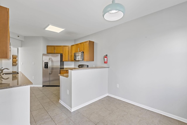 kitchen featuring stone counters, appliances with stainless steel finishes, kitchen peninsula, and sink