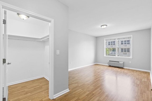 unfurnished living room with a wall unit AC and hardwood / wood-style floors