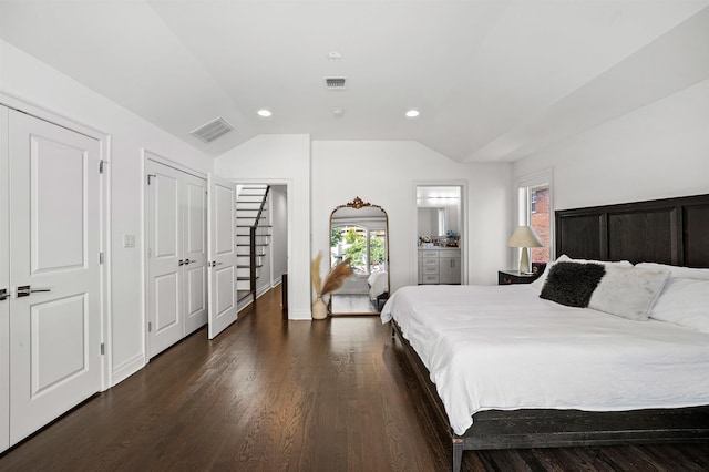 bedroom with ensuite bath, lofted ceiling, and dark wood-type flooring