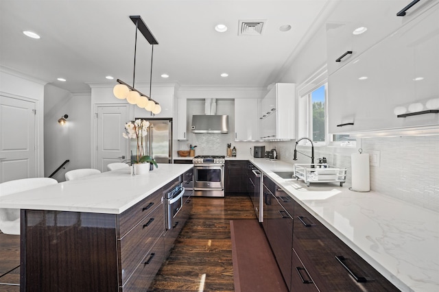 kitchen with sink, decorative light fixtures, stainless steel appliances, white cabinets, and a breakfast bar area