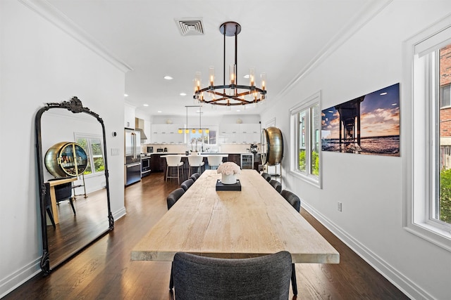 dining space featuring a notable chandelier, ornamental molding, and dark hardwood / wood-style floors