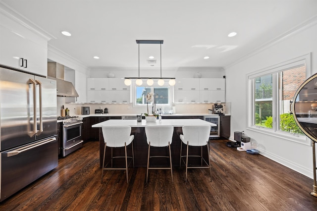 kitchen featuring hanging light fixtures, an island with sink, stainless steel appliances, and white cabinets