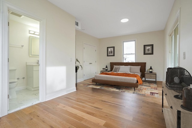 bedroom with ensuite bathroom, a closet, and light wood-type flooring