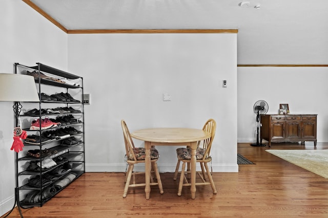 dining room with crown molding and light hardwood / wood-style flooring