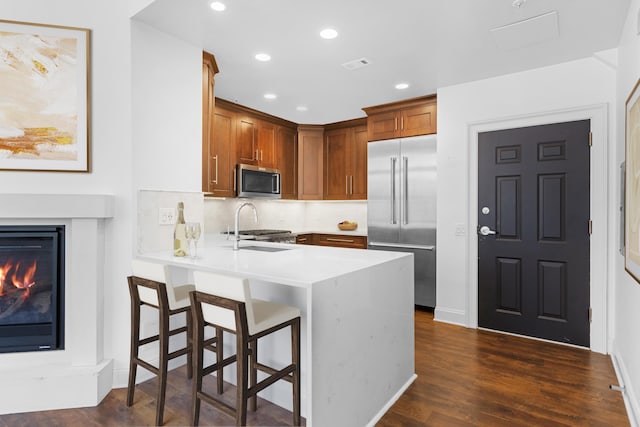 15 Warren St Unit 102, Jersey City, NJ 07032 - kitchen with stainless steel appliances, a peninsula, light countertops, a breakfast bar, and dark wood finished floors