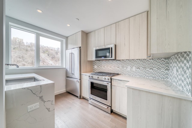 800 Ave At Port Imperial Unit 323, Weehawken, NJ 07086 - kitchen with stainless steel appliances, modern cabinets, light wood finished floors, decorative backsplash, and light stone counters