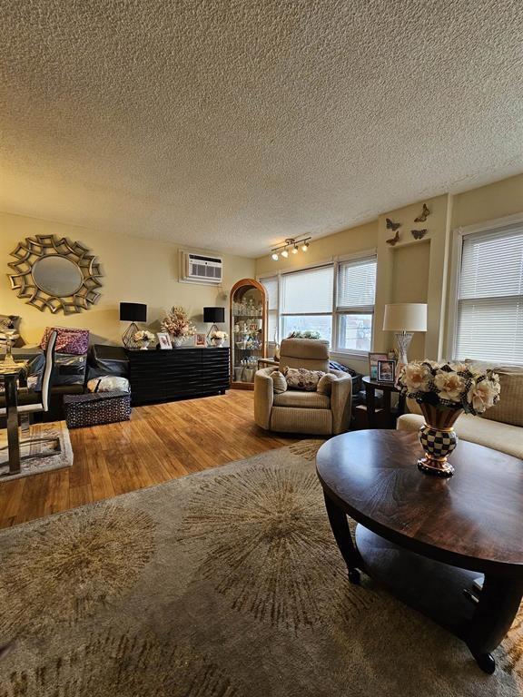 living room featuring a textured ceiling, a wall mounted AC, and wood finished floors