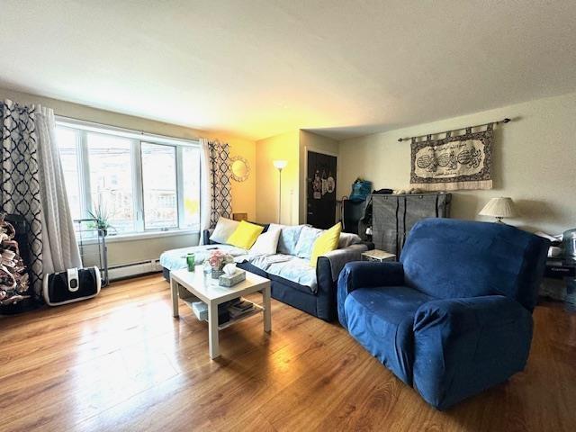 living room with wood finished floors and a baseboard heating unit