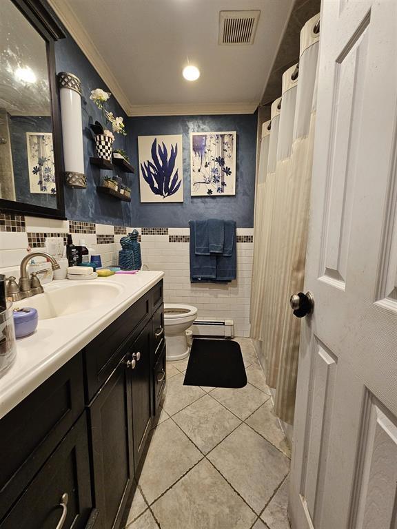 bathroom with visible vents, toilet, tile walls, tile patterned floors, and a baseboard heating unit