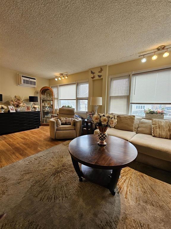 living room with track lighting, a textured ceiling, and wood finished floors