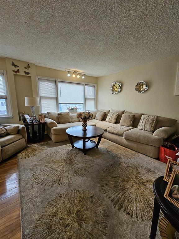 living room featuring track lighting, a textured ceiling, and hardwood / wood-style floors