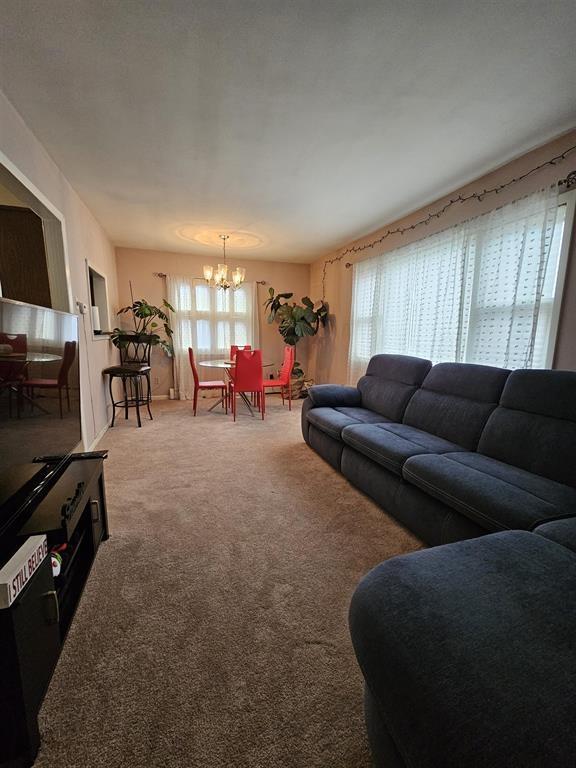 carpeted living room with a healthy amount of sunlight and a chandelier