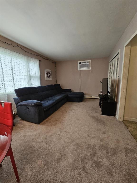 living room featuring carpet and a wall mounted air conditioner