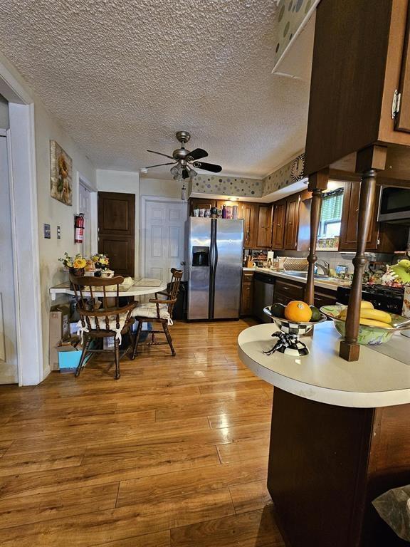 kitchen featuring light countertops, a textured ceiling, a ceiling fan, light wood-style flooring, and appliances with stainless steel finishes