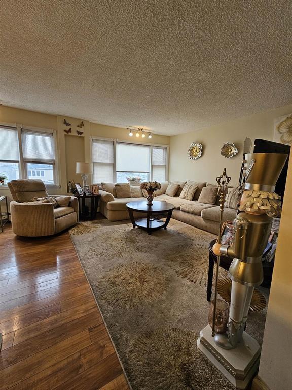 living room featuring a textured ceiling and dark wood-style floors