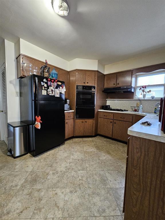 kitchen featuring light countertops, black appliances, and under cabinet range hood
