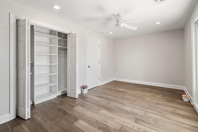 unfurnished bedroom featuring ceiling fan, a closet, and hardwood / wood-style flooring