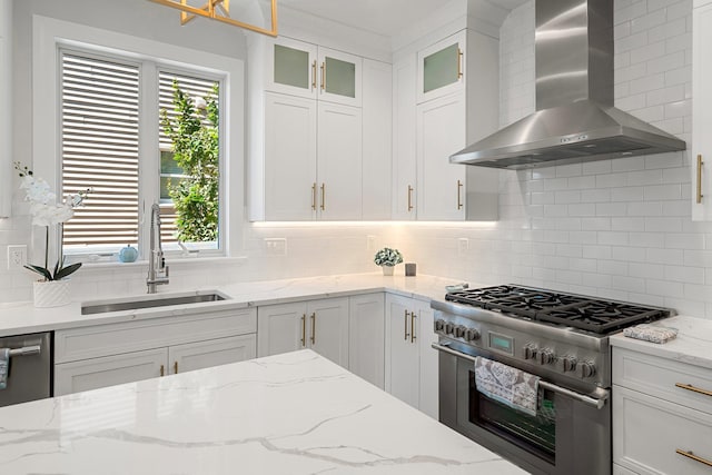 kitchen with white cabinetry, sink, stainless steel appliances, wall chimney range hood, and tasteful backsplash