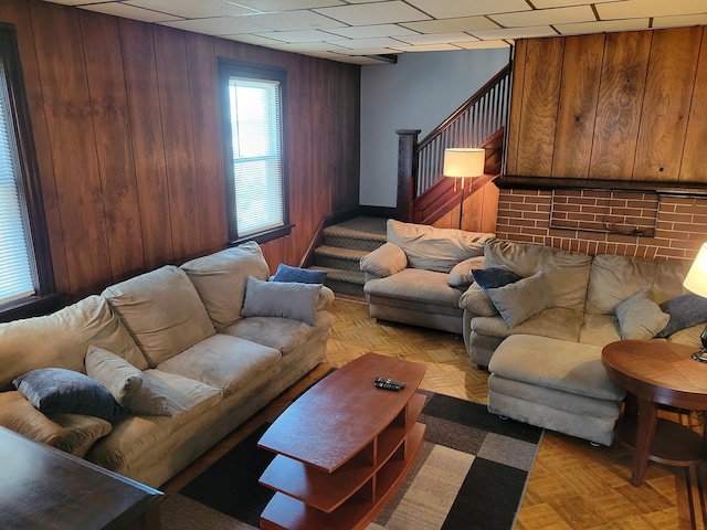 living room featuring baseboards, wood walls, and stairway