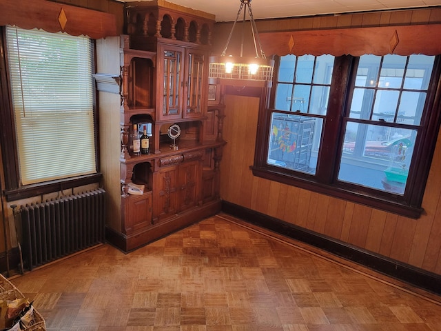 dining space featuring baseboards, wood walls, and radiator heating unit