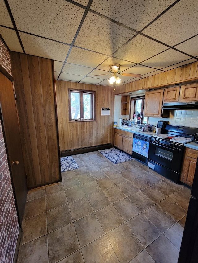 kitchen with wooden walls, black range oven, under cabinet range hood, and dishwashing machine