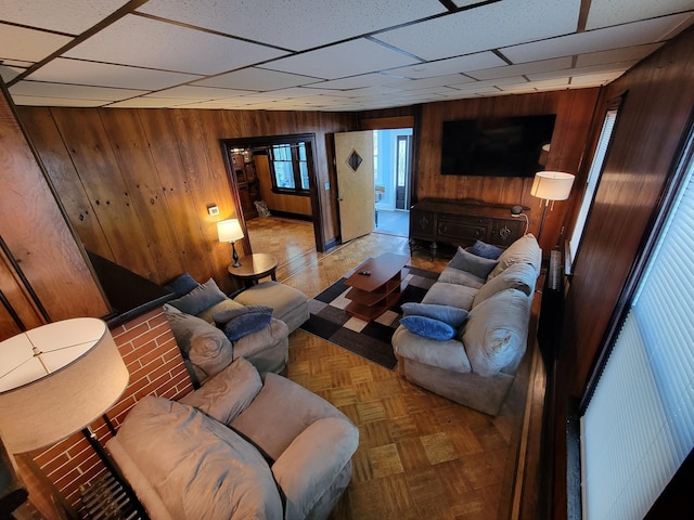 living room with wooden walls and a drop ceiling