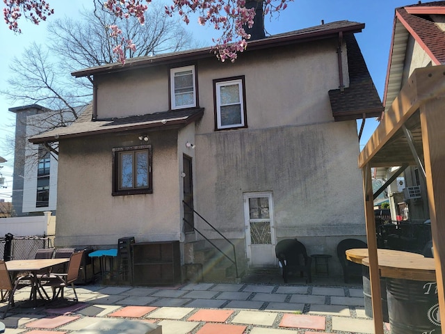 rear view of property with a patio, fence, and stucco siding