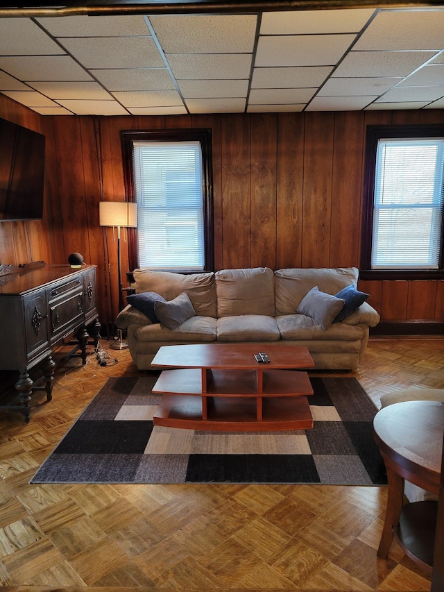 living area with wood walls and a drop ceiling
